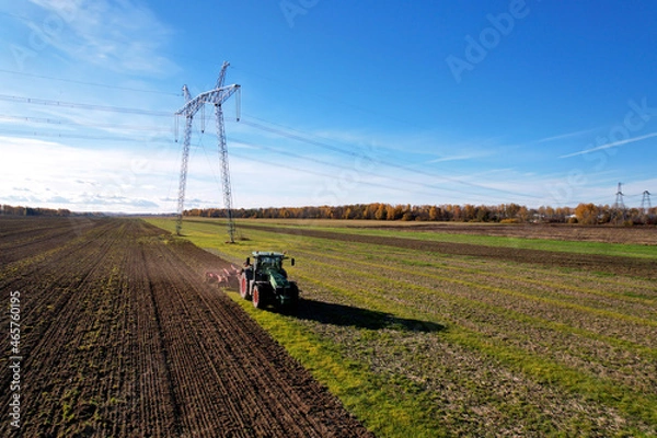 Fototapeta Tractor with Plough on Plowed. Ploughing and Soil Tillage. Agricultural Tractor on Cultivation Field for Sowing Seeds. Tractor During Field Cultivating. Planting and Seeding Equipment.