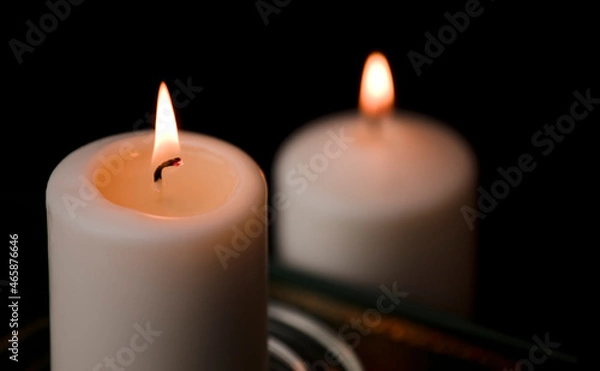 Obraz two burning candles isolated with black background