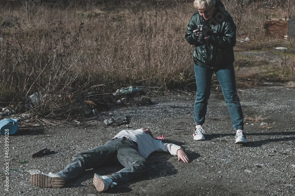 Obraz a female forensic expert photographs a dead homeless girl killed during the war on the road at a checkpoint