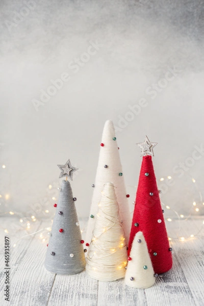 Fototapeta Handmade Christmas trees. Yarn wrapped cone trees and garland. Craft decorations to decorate your home during the holidays