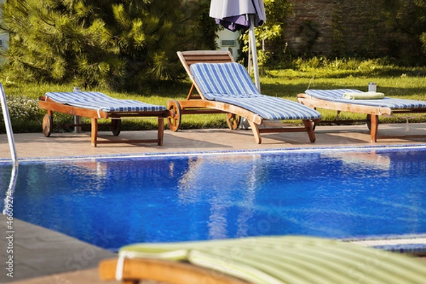 Obraz deck chairs on the edge of the beautiful blue pool filled with w