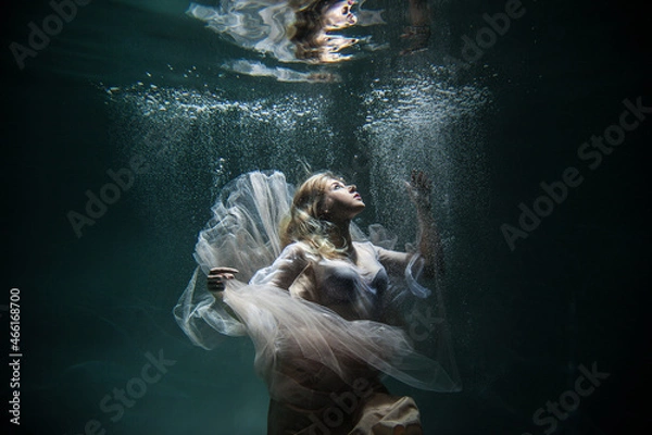 Obraz Girl in a white dress underwater around a lot of bubbles on a dark background