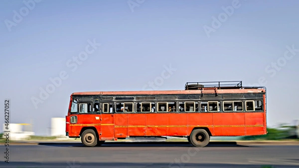 Fototapeta Background blur, pan image of non air-conditioned red intercity bus in Maharashtra, speeding on the street.