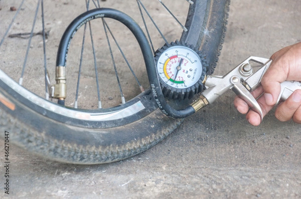Fototapeta Close up mechanic's hand  Measure quantity Inflated Rubber tires bicycle. mechanic inflating tire and checking air pressure with gauge pressure 
