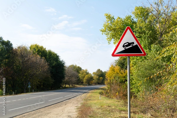 Obraz Triangular road sign steep climb against the background of autumn trees near the track