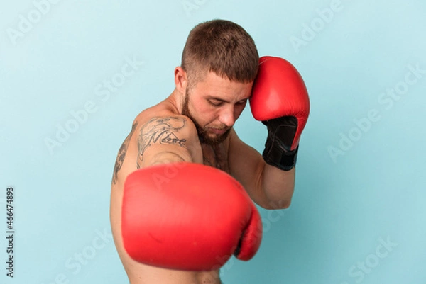Fototapeta Young caucasian man practicing boxing isolated on blue background