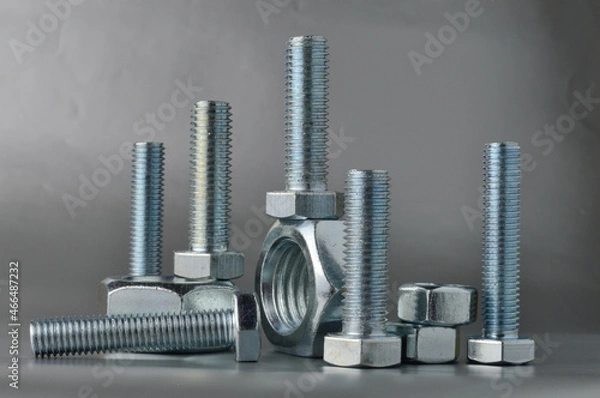 Fototapeta composition of new bolts and nuts of different sizes on a gray background.