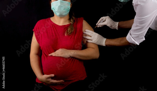 Obraz pregnant woman getting covid-19 vaccine on black background