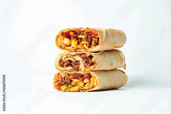 Fototapeta Shawarma stacked one on top of the other with meat and vegetable filling. A stack of shawarma on a white background. Selective focus