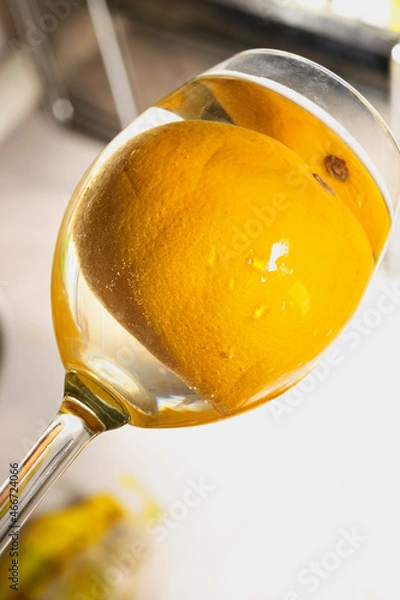 Obraz dynamic shooting angle from below on a glass with a whole orange in a drink in a glass. Refreshing lemonade concept.