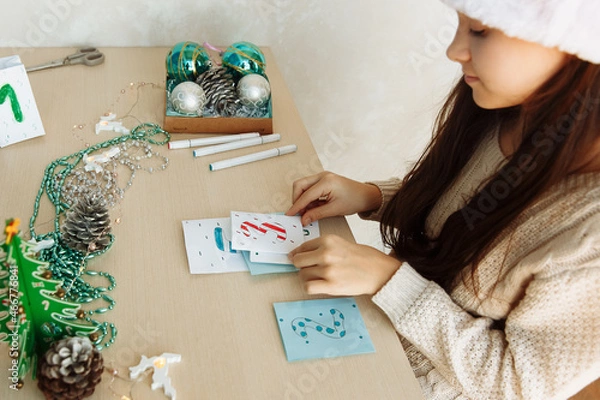 Obraz a child makes a Christmas advent calendar out of paper with his own hands diy close up