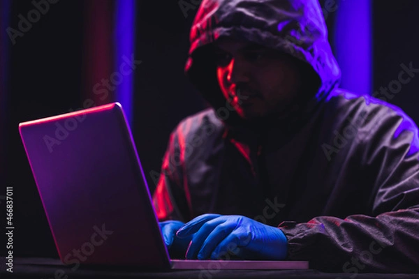 Fototapeta Hackers wear hoods to cover their faces. Hacking to steal important information. Use a computer to release malware viruses Ransom and harass organizations. He sitting in the dark room with neon light