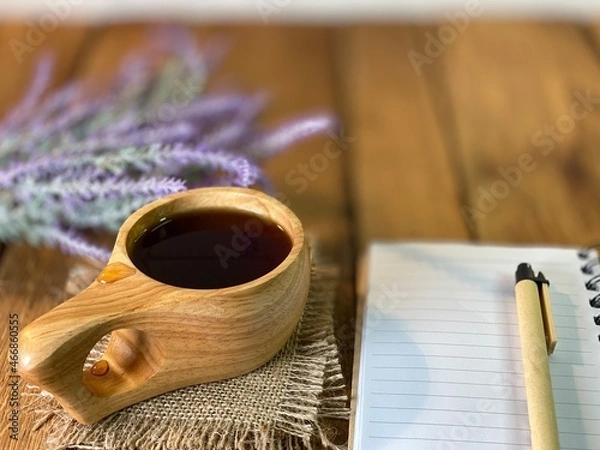 Fototapeta background made of oak planks and pine planks painted white on the table a bunch of lavender and a wooden cup with coffee and a notebook and a pen