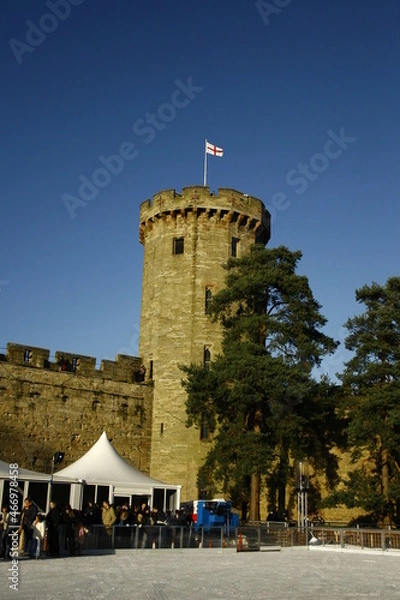 Fototapeta old British Castle in warwick westmidlands in golden autumn light with the blue sky background during autumn
