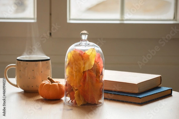 Fototapeta Table with books, cup of coffee or tea with autumn deco arrangement, colourful leaves and mini pumpkin. Reading books at home, cosy, lazy atmosphere. Leisure activities, relaxing at home during autumn
