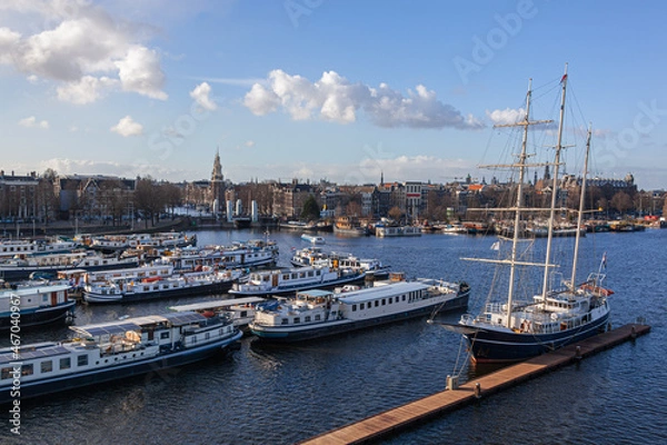 Fototapeta Scenic Amsterdam harbor with boats, ships and traditional sailing barque on the panoramic city view background, Netherlands