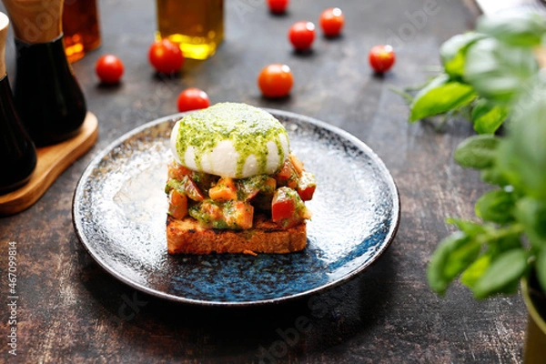 Obraz Bruschetta with burrata and basil pesto.
Appetizing dish. Culinary photography, a proposal to serve a meal.