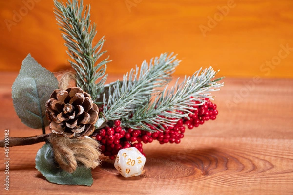 Fototapeta One single D20 role playing white dice on a gaming table made of wood stay near Christmas tree. Dungeons and Dragons role-playing games