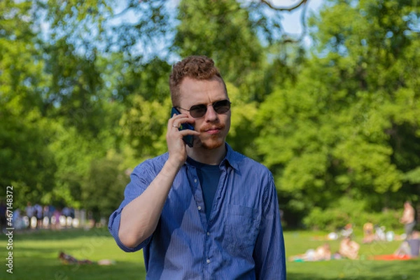 Fototapeta a man is talking on the phone in the park