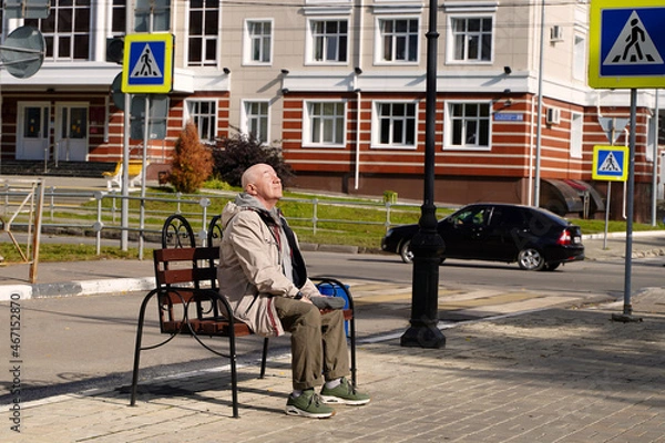 Fototapeta Elderly man resting on a bench and enjoying the sun