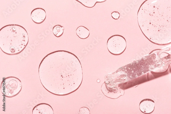 Obraz Drops of anti-aging emulsion and glass pipette tip on light pink surface close upper view. Skincare and dermatological procedures