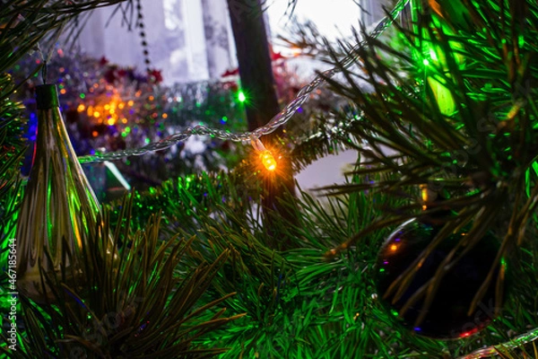 Fototapeta Glow of a light bulb in a garland on a christmas tree in the dark