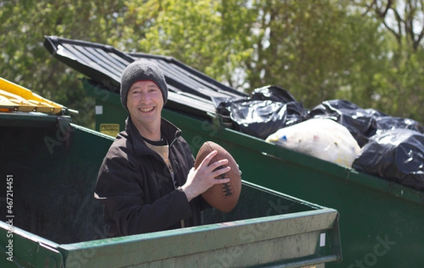 Fototapeta man holding football while standing in a dumpster