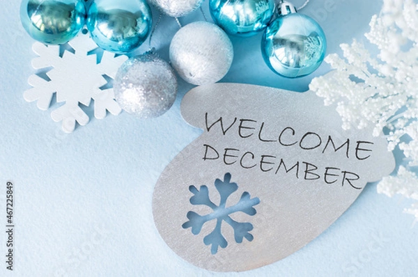 Fototapeta Welcome December, the inscription on a wooden toy in the shape of a mittens next to a new ball and snowflake, festive background