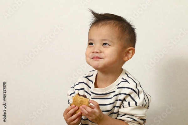 Fototapeta 日本のスイーツ、鯛焼きを美味しく食べている男の子。