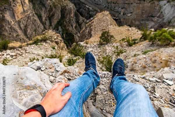 Fototapeta View of the feet of a male traveler in sneakers on a hilltop enjoying the view