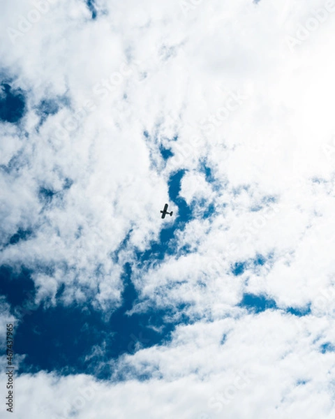 Fototapeta Nadir view of a passing airplane against a cloud-filled background