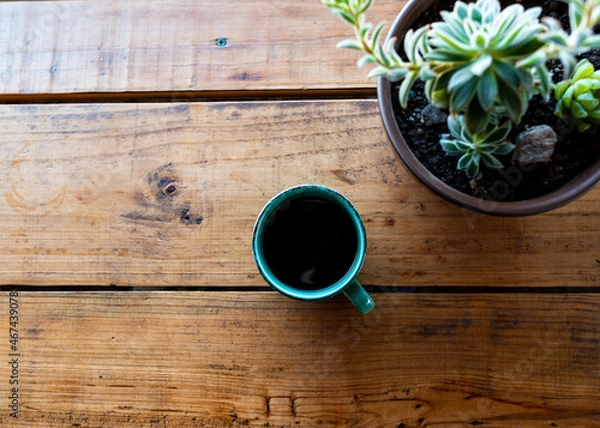 Fototapeta Top view of a coffee cup on a wooden table with a succulent plant on the side.