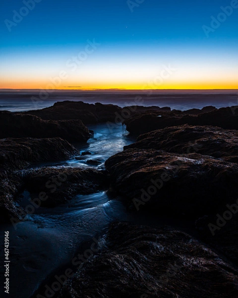 Fototapeta Beautiful twilight on the shores of pichilemu beach with waves crashing against the rocks on the shore.