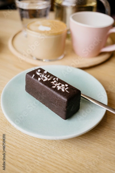Obraz Tasty vegan row chocolate dessert on plate on background of coffee and tea mugs. Сozy coffee shop. 