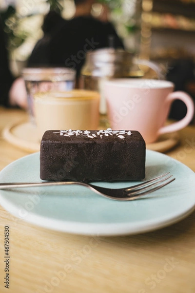 Fototapeta Chocolate dessert bar with coconut flakes on background of coffee and other drinks. Coffee shop or cafe with pastry. 