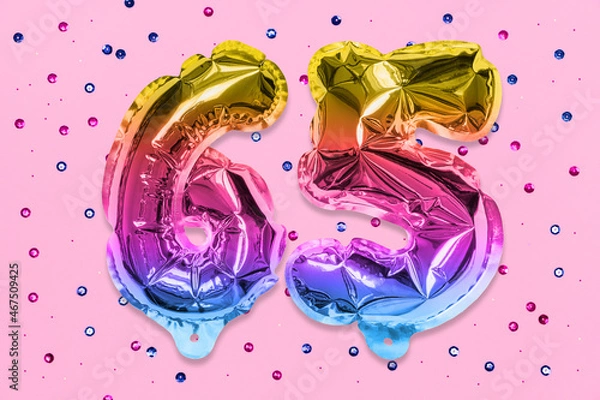 Fototapeta Rainbow foil balloon number, digit sixty five on a pink background with sequins. Birthday greeting card with inscription 65. Anniversary concept. Numerical digit. Celebration event, template.