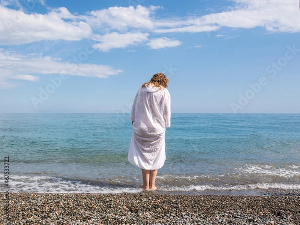 Fototapeta Red-haired woman in a white robe on the seashore