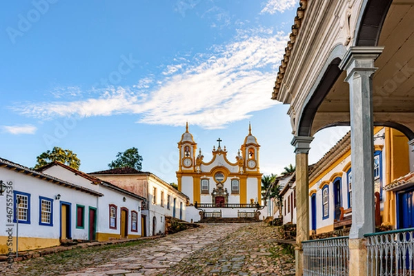 Obraz A quiet historic street in the city of Tiradentes in Minas Gerais with colonial houses and a baroque church in the background
