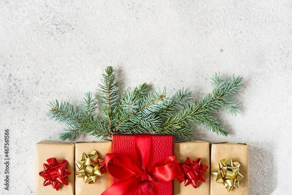 Fototapeta Many small gift boxes with a large red box in the center, wrapped in holiday paper with fir branches on gray background. Gifts for Christmas and New Year. Festive concept, top view.