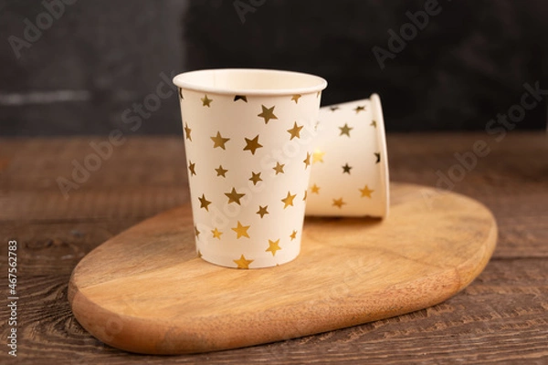 Obraz Realistic table after birthday or Christmas party. Beautiful wooden table, white paper cups, copy space. Concept of celebration at home.