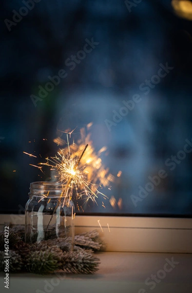 Obraz Christmas or New Year party sparkler in a jar in front of the window on dark background. Xmas decoration
