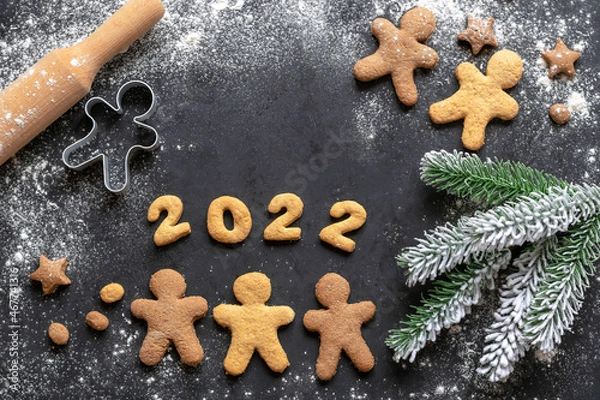 Obraz Gingerbread men and a branch of a Christmas tree. New Year's background. 2022 year.