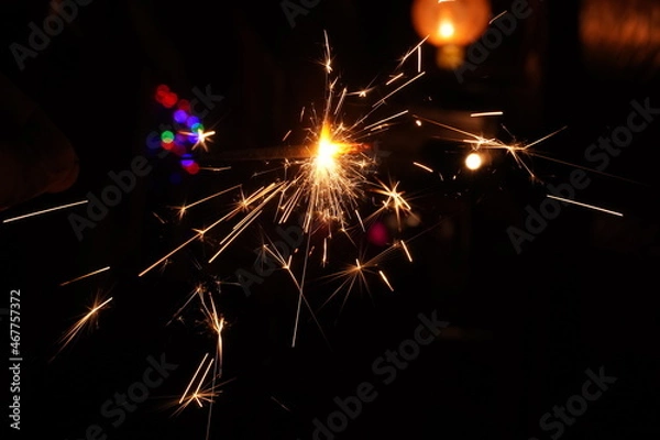 Fototapeta A burning sparkler on the black