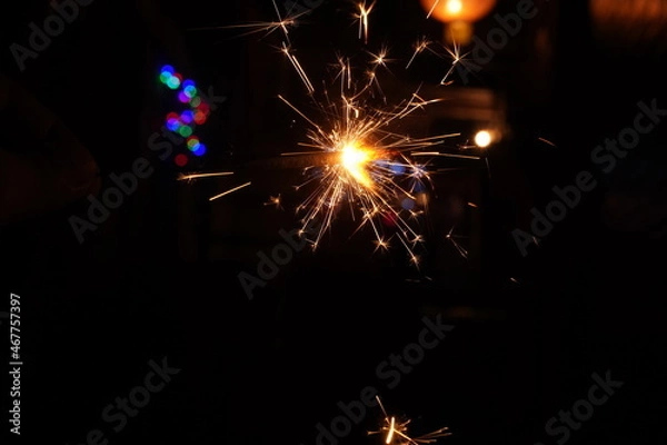 Fototapeta A burning sparkler on the black