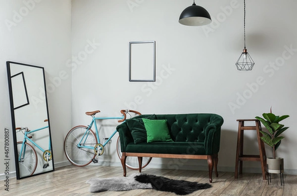 Fototapeta Interior of light living room with green sofa, mirror and bicycle