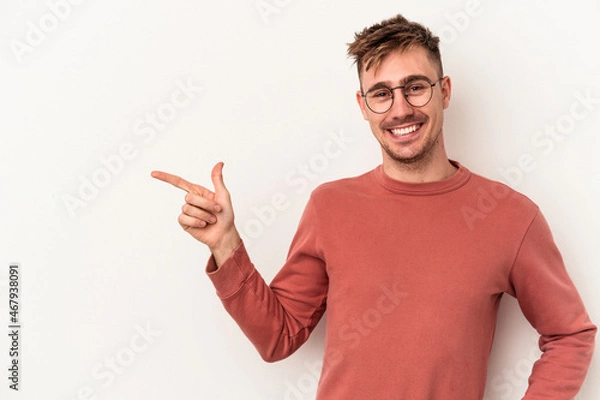 Fototapeta Young caucasian man isolated on white background smiling cheerfully pointing with forefinger away.