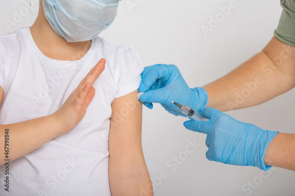 Fototapeta Close-up of a woman's hands in protective gloves holding a covid 19 vaccination syringe. The girl gets an injection in the shoulder. Concept of clinical trials of a vaccine for children, coronavirus