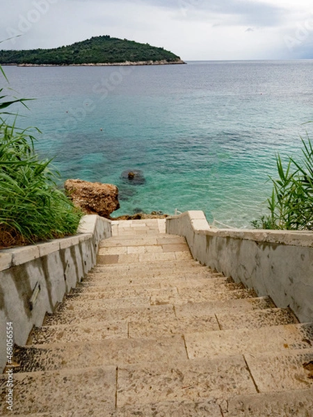Fototapeta Stone steps leading down to beach of blue Adriatic Sea in Dubrovnik, Croatia. wit island in the background. 