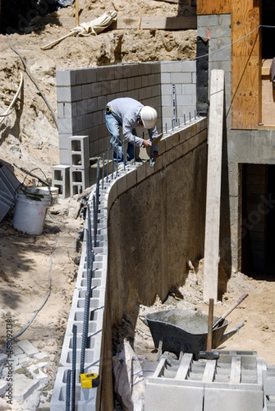 Fototapeta Block mason working on a large retaining wall