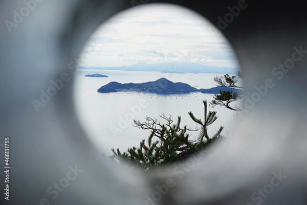 Obraz looking through binoculars at an island on a cloudy day